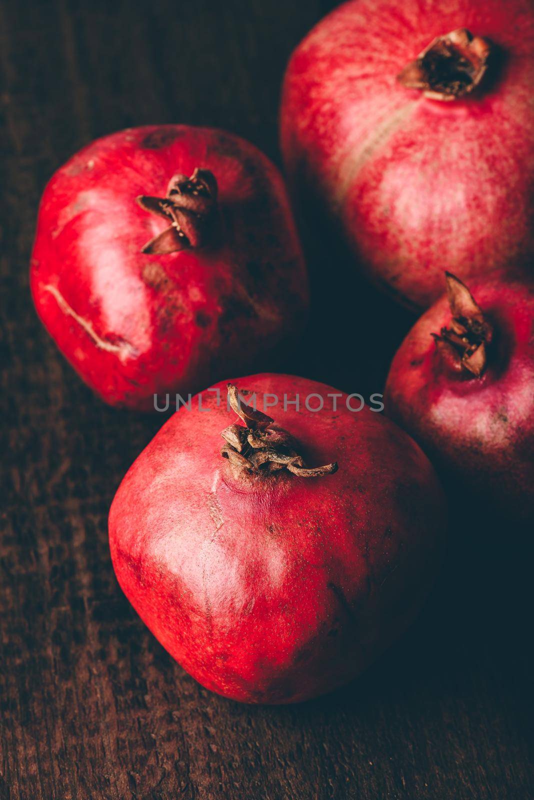 Four ripe pomegranate on rustic wooden table