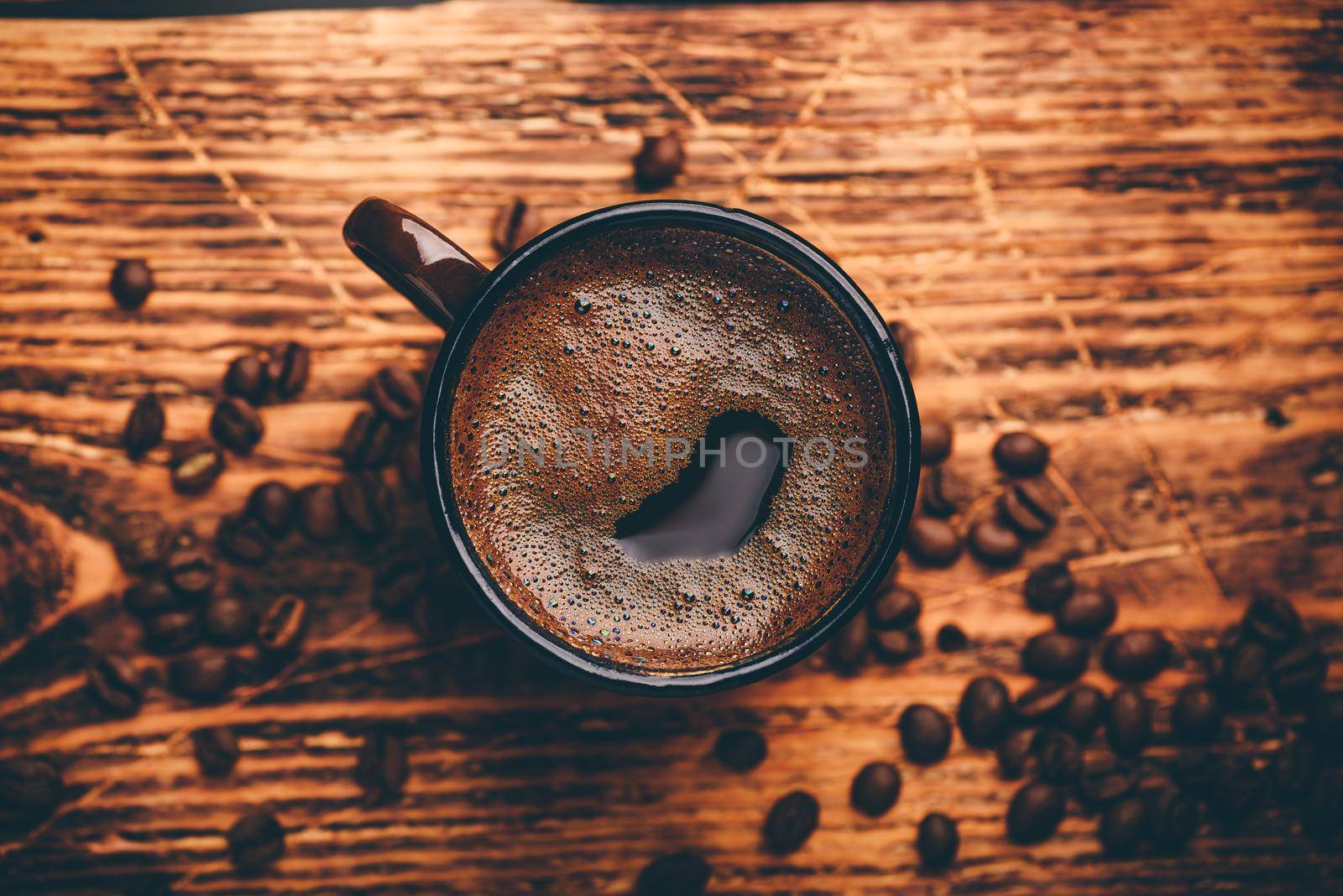 Brewed black coffee in metal mug over wooden surface