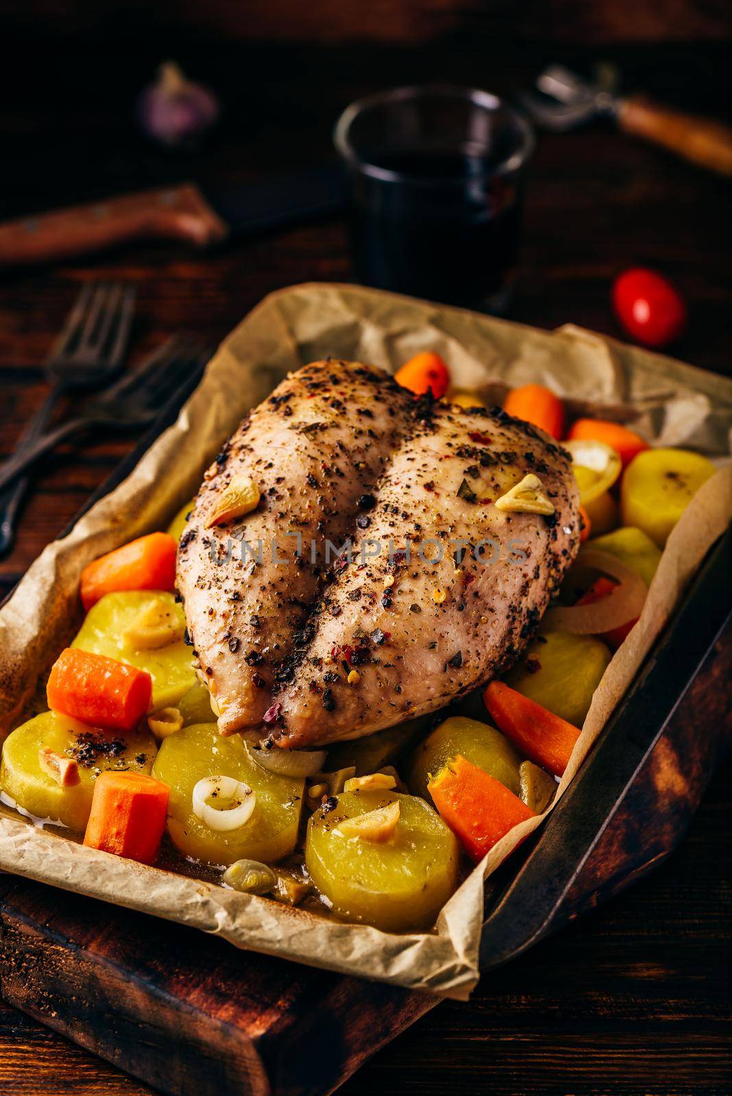 Seasoned chicken breast baked in oven with vegetables on baking sheet