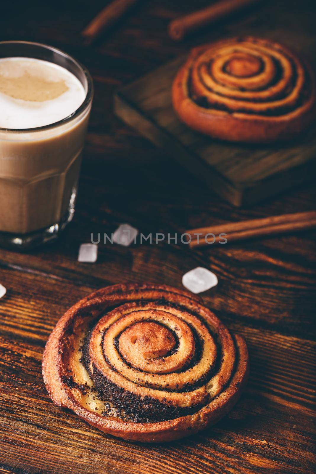 Sweet roll with poppy seeds. Glass of cappuccino and sugar