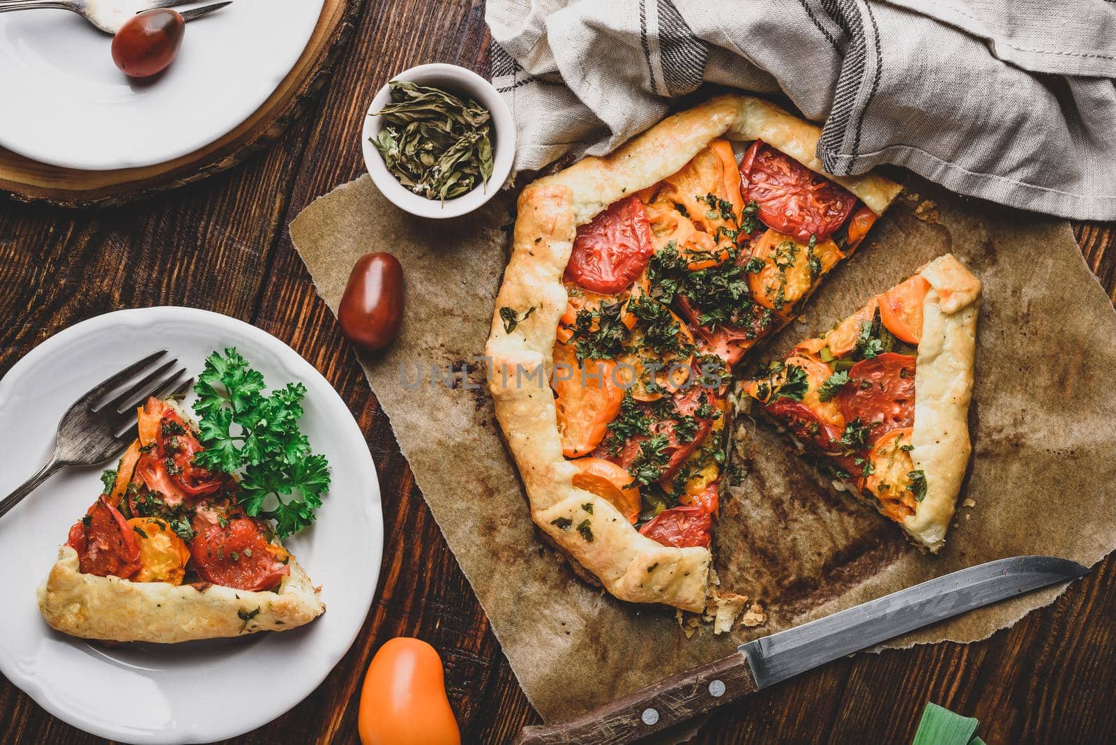 Freshly baked and sliced tomato galette on baking paper. View from above