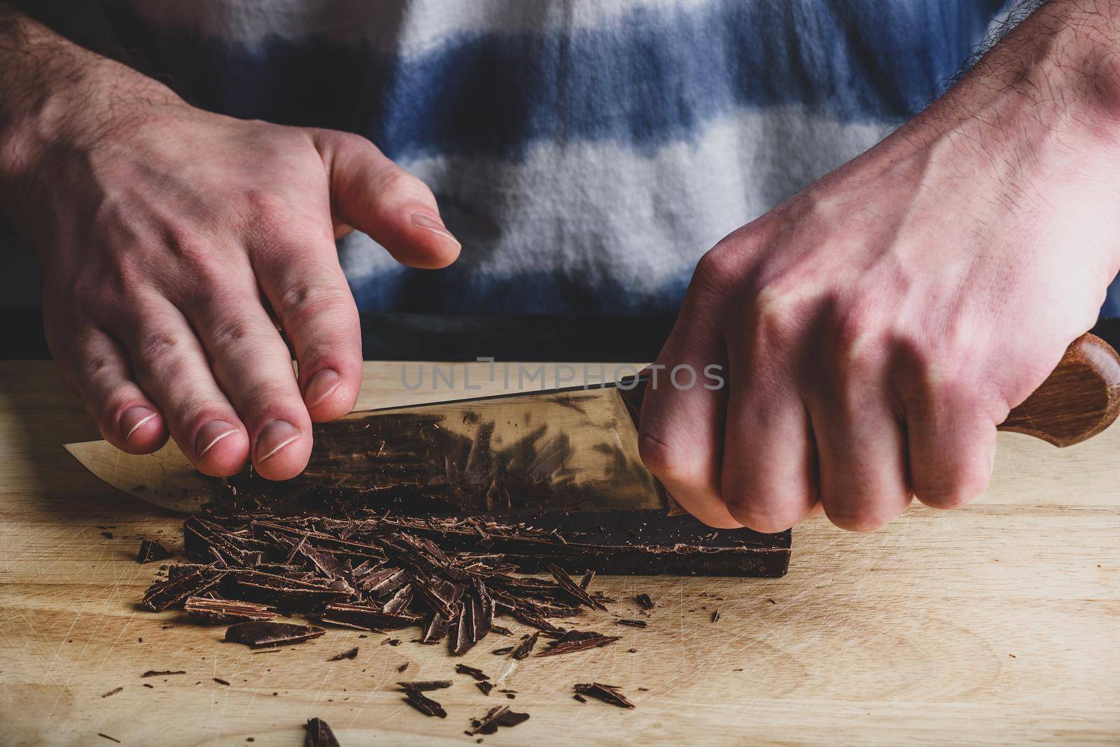 Roughly chopping dark chocolate bar with knife