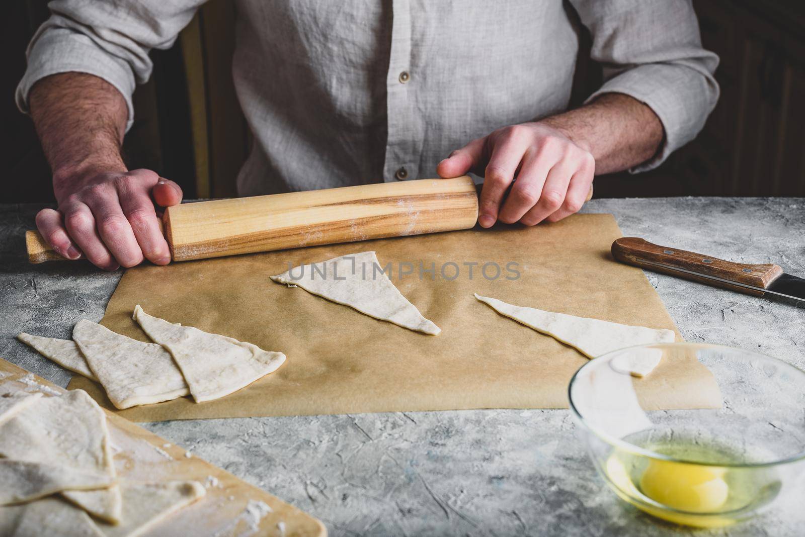 Baker rolls the puff pastry for croissants by Seva_blsv