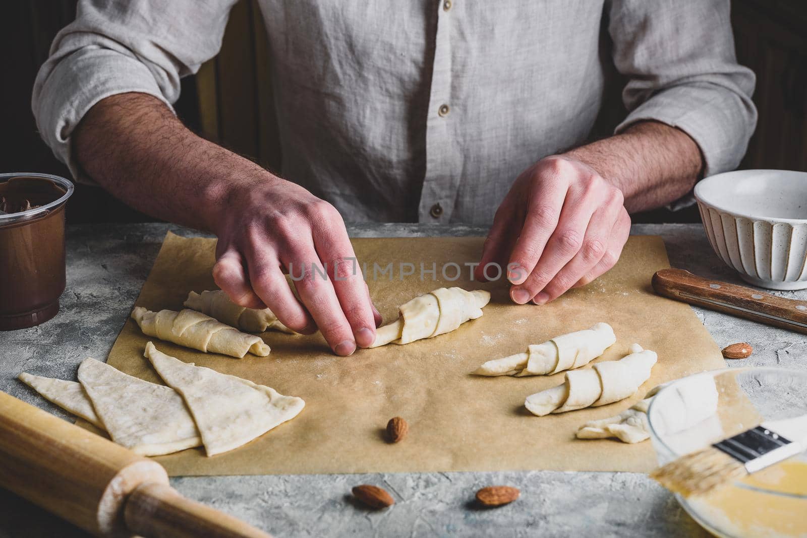 Croissant preparing. Baker rolls the puff pastry stuffed with almonds and spread by Seva_blsv