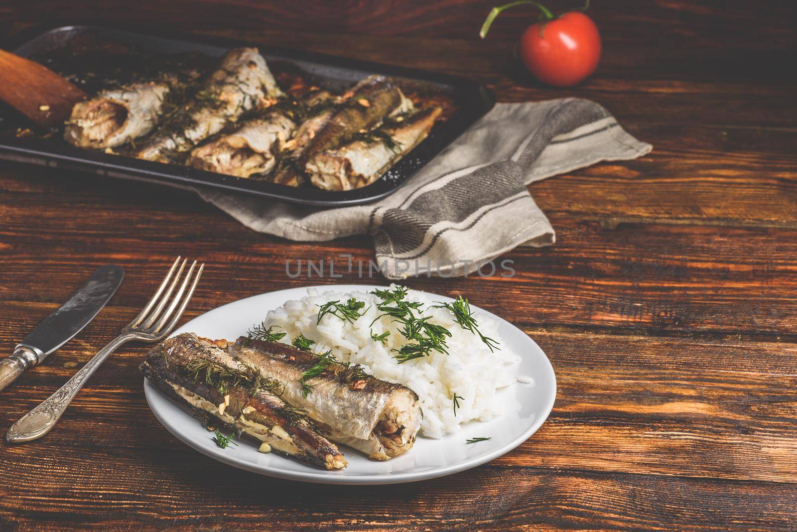 Baked hake carcasses with rice on white plate