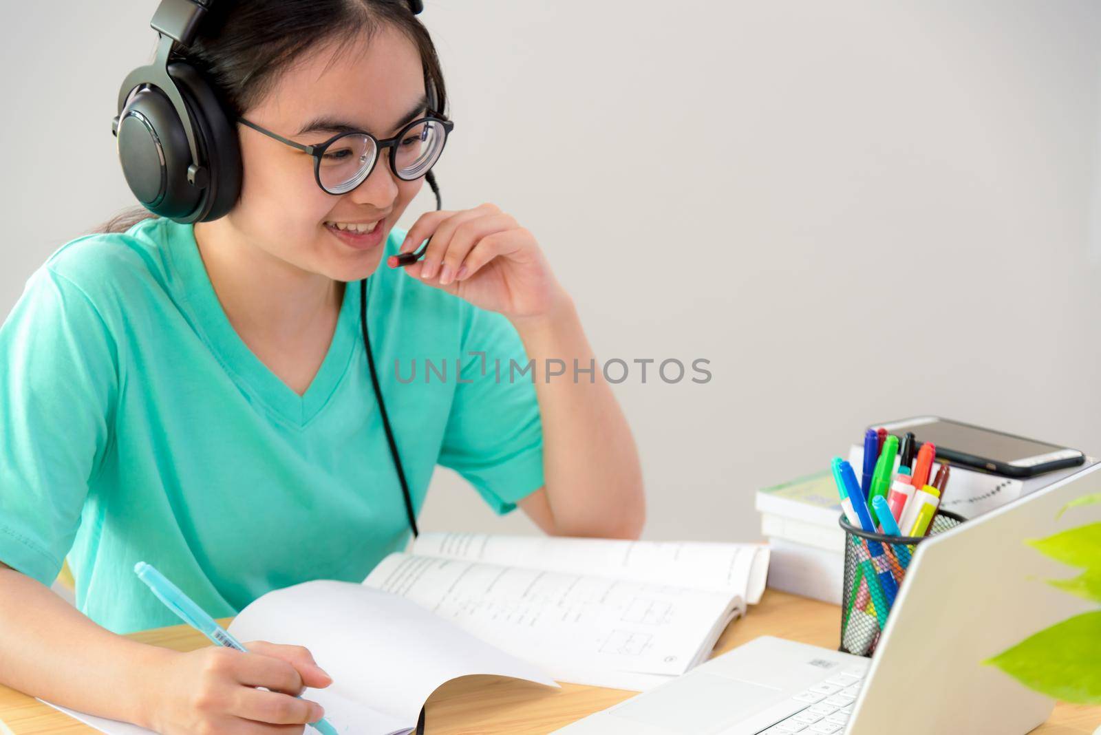 Asian woman looking to talk video conference calling on a laptop computer girl students speak respond with headset microphone class university learning internet online distance education from home