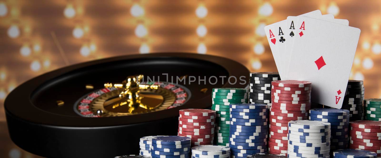 Poker Chips on gaming table, roulette wheel in motion, casino background  by JanPietruszka