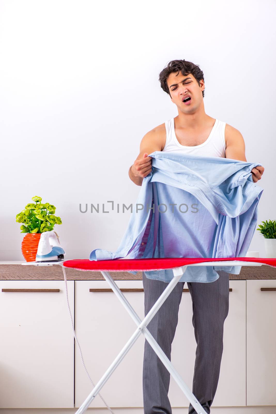 Young man ironing in the bedroom 