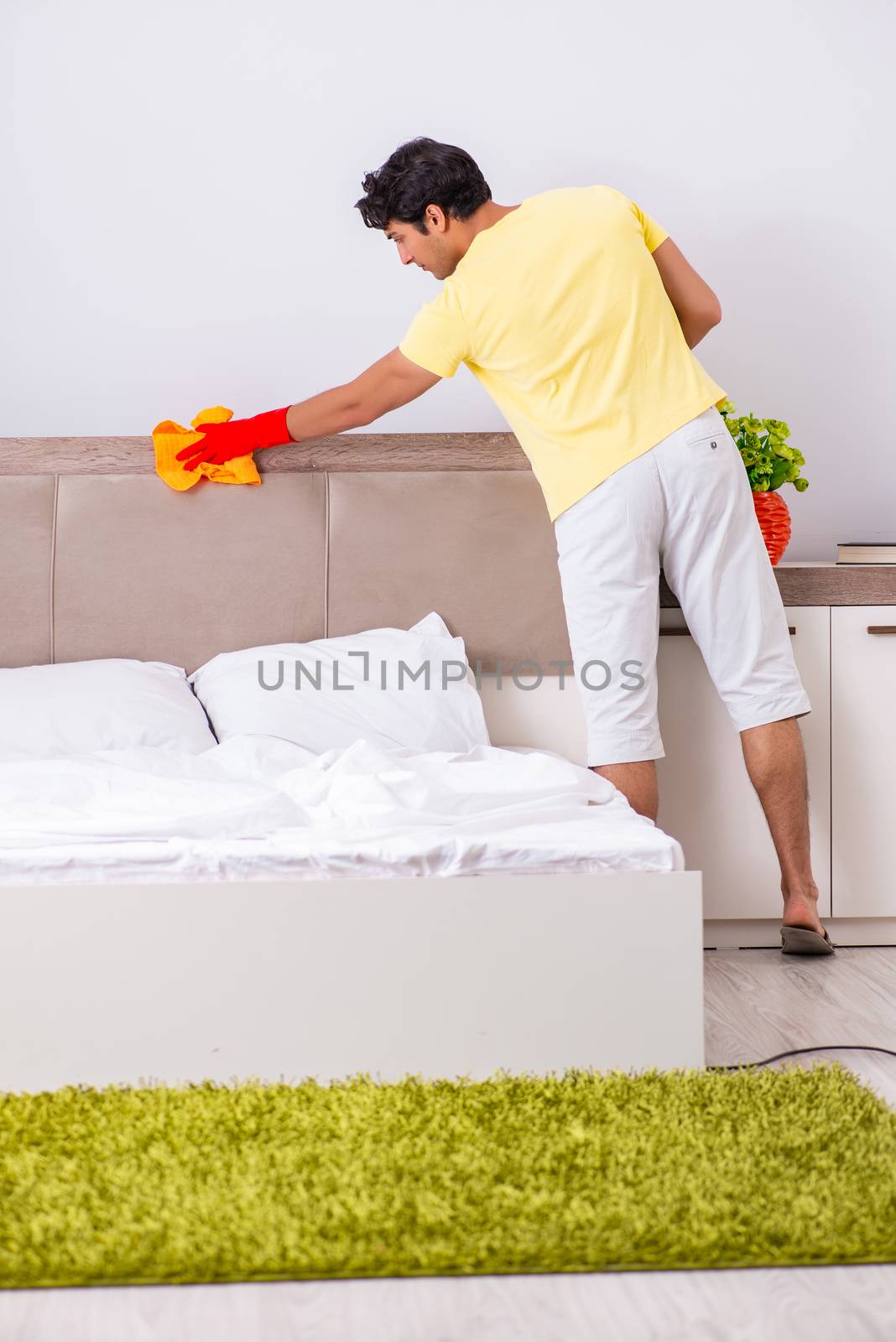 Young handsome man cleaning in the bedroom