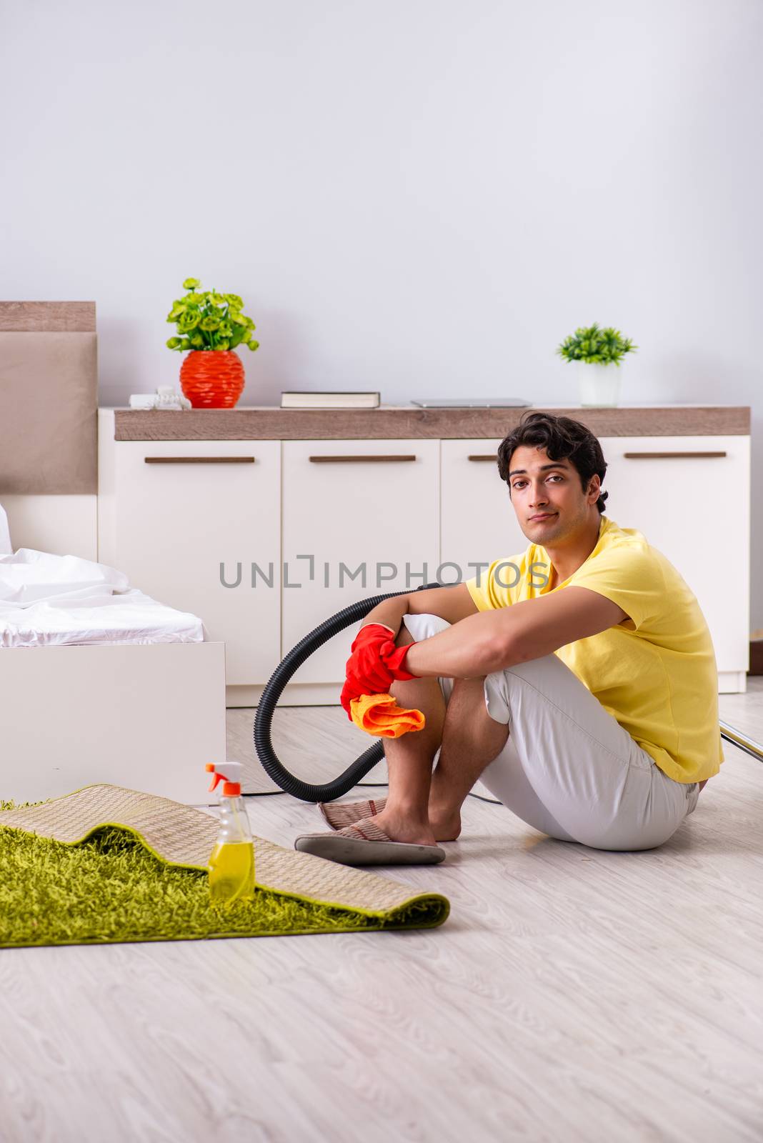 Young handsome man cleaning in the bedroom