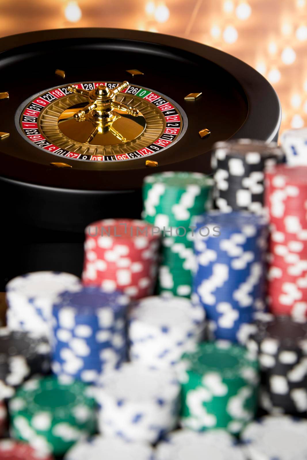 Poker Chips on gaming table, roulette wheel in motion, casino background  by JanPietruszka