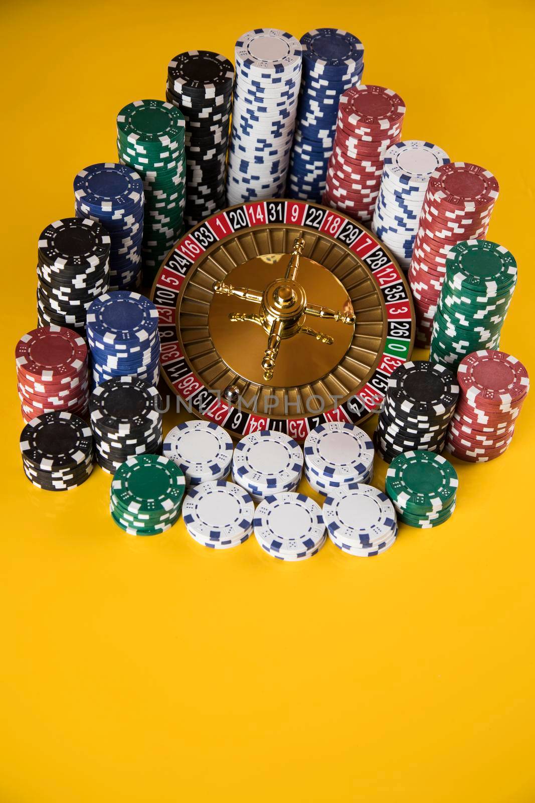 Poker Chips on gaming table, roulette wheel in motion, casino background  by JanPietruszka