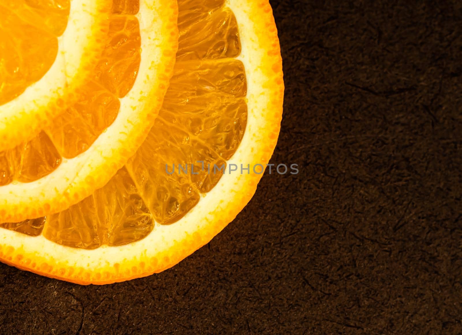 Part of orange slices on a dark background. Place for your text