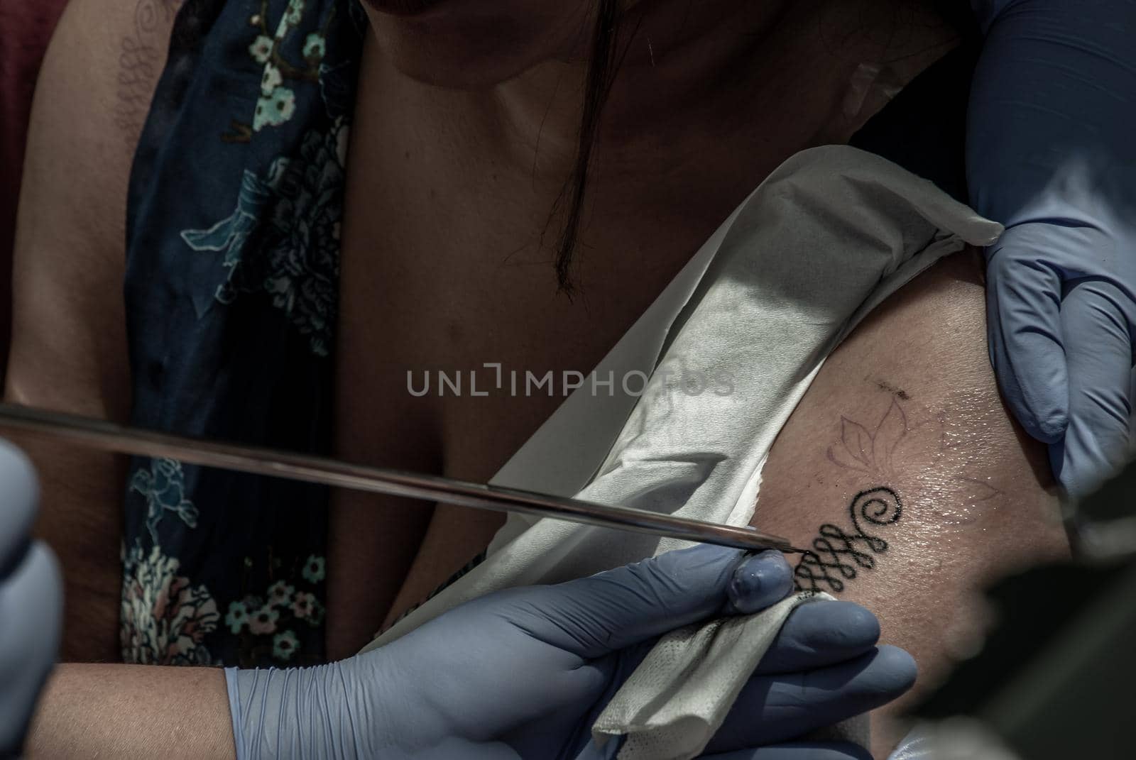 Bangkok, Thailand - 25 Aug 2019 : Tattooing Thai style concepts. Tattoo artist creating a tattoo on a girl's arm with a pointed metal.