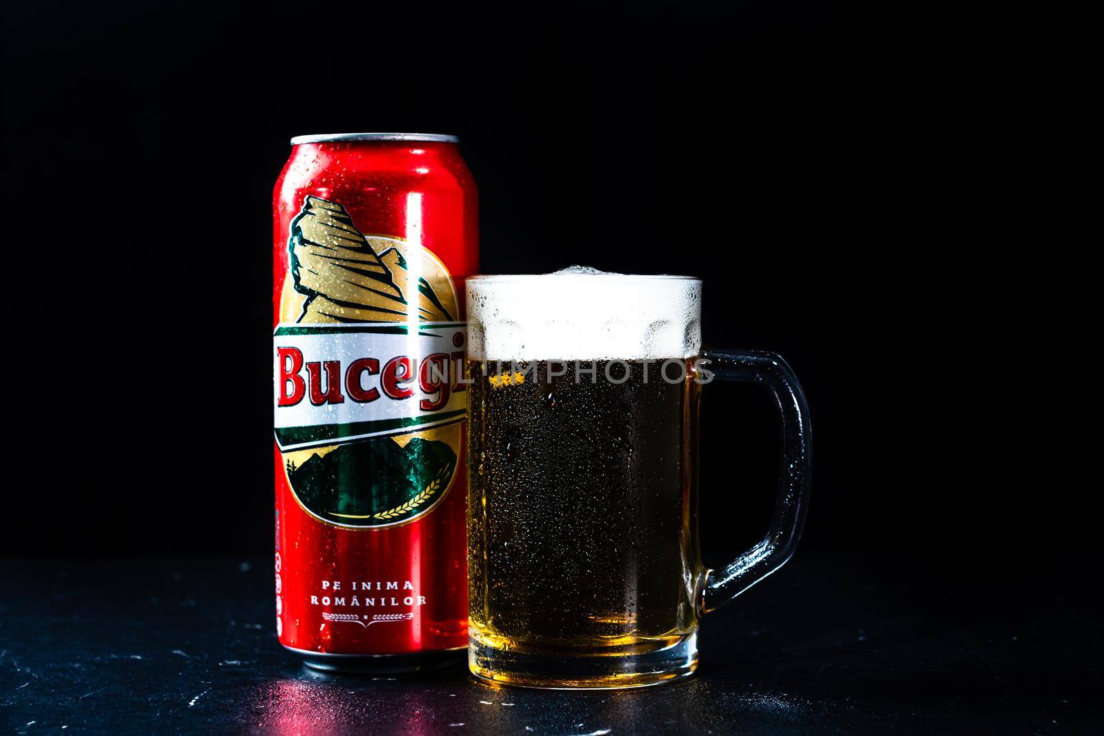 Can of Bucegi beer and beer glass on dark background. Illustrative editorial photo shot in Bucharest, Romania, 2021 by vladispas