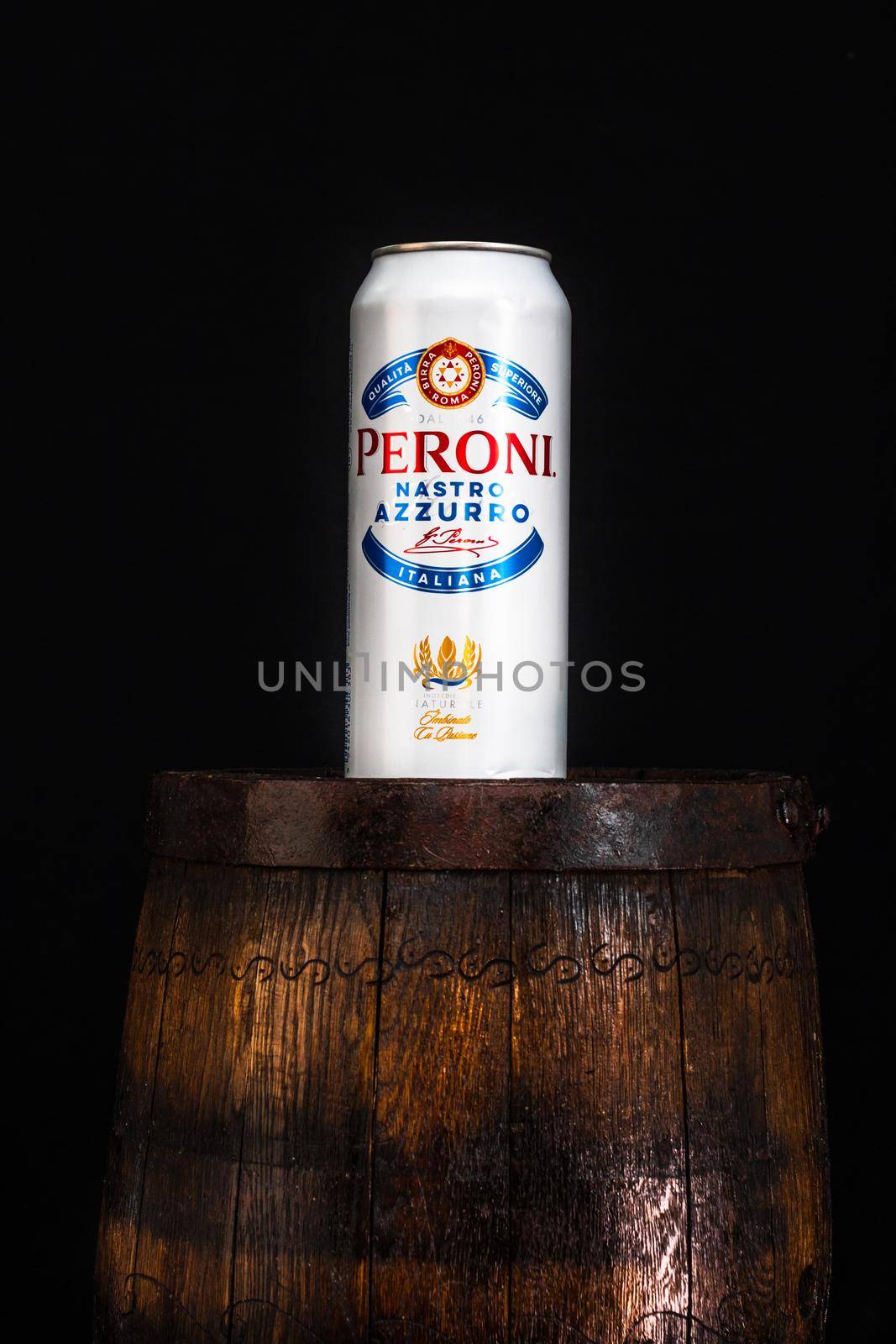Can of Peroni beer on beer barrel with dark background. Illustrative editorial photo Bucharest, Romania, 2021 by vladispas