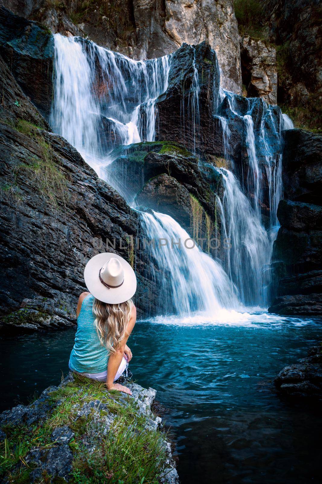 Female sitting by a tumbling waterfall and natural rock pool by lovleah