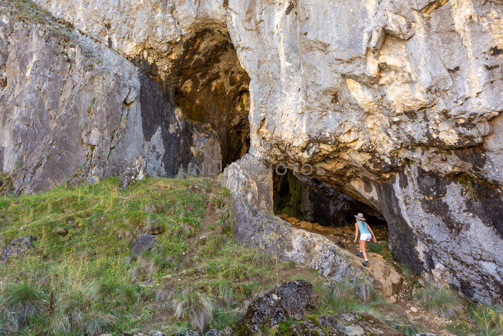 Female explorer entering a cave system in mountainous terrain in Australia