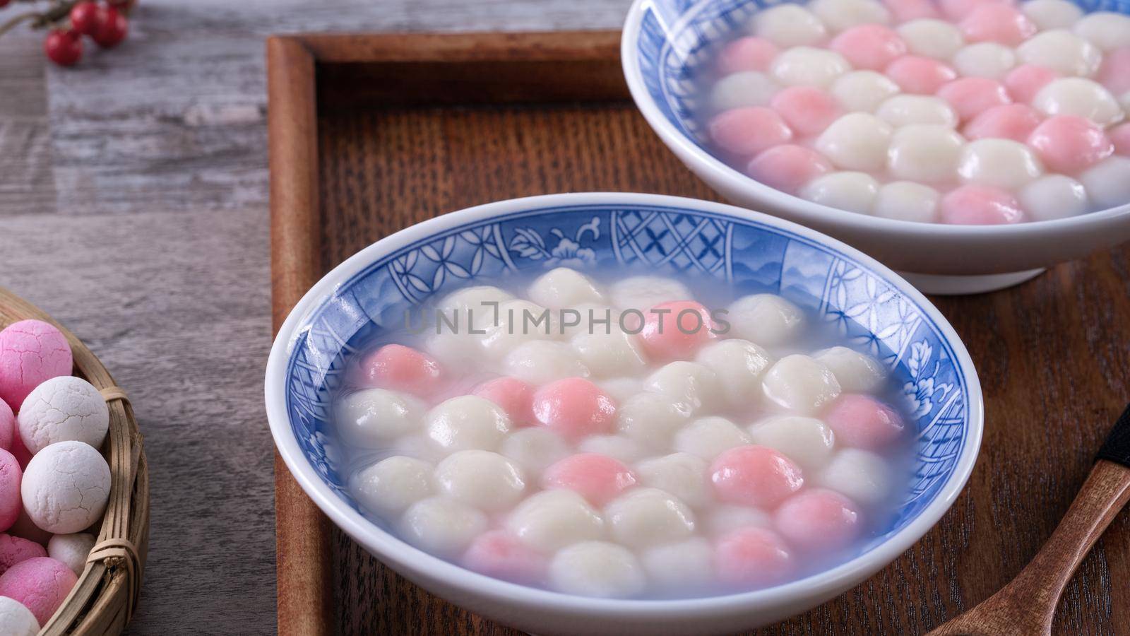 Close up of red and white tangyuan (tang yuan, glutinous rice dumpling balls) in blue bowl on wooden background for Winter solstice festival food.