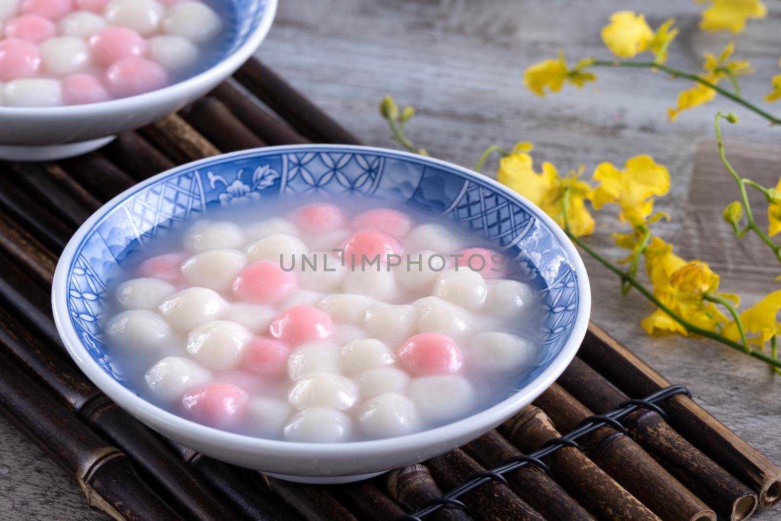 Close up of red and white tangyuan (tang yuan, glutinous rice dumpling balls) in blue bowl on wooden background for Winter solstice festival food.