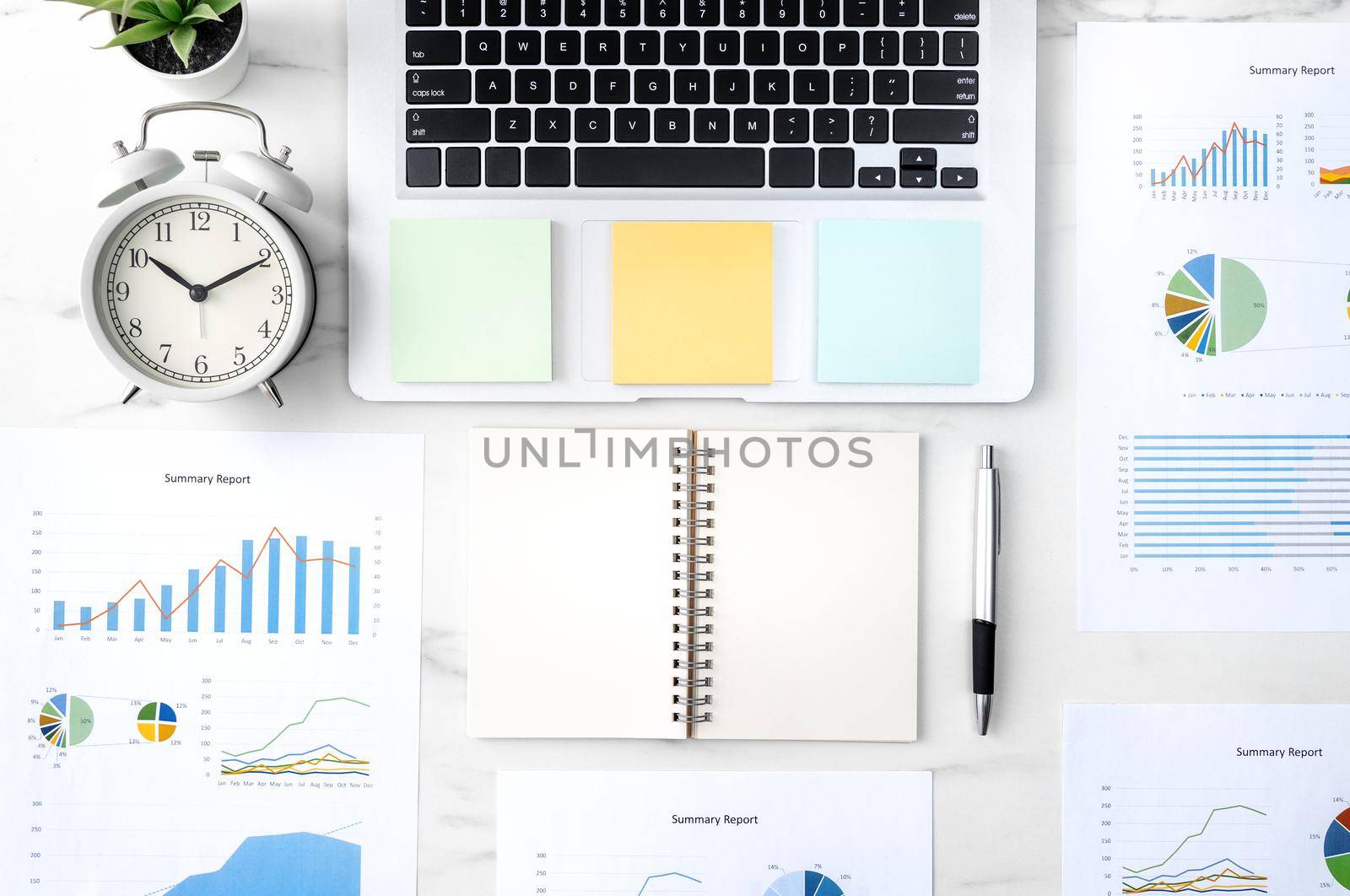 Top view of office table desk work concept with blank notebook, report, alarm clock on marble white background, concept of timing management and schedule planning.