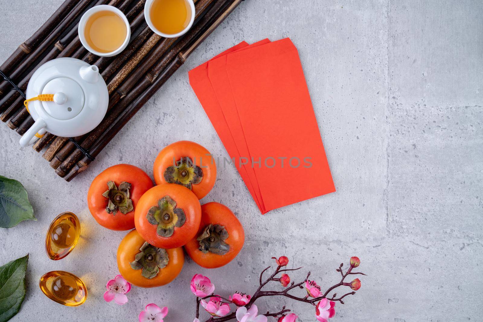 Top view of fresh sweet persimmons kaki with leaves on gray table background for Chinese lunar new year fruit design concept, the word means spring is coming.