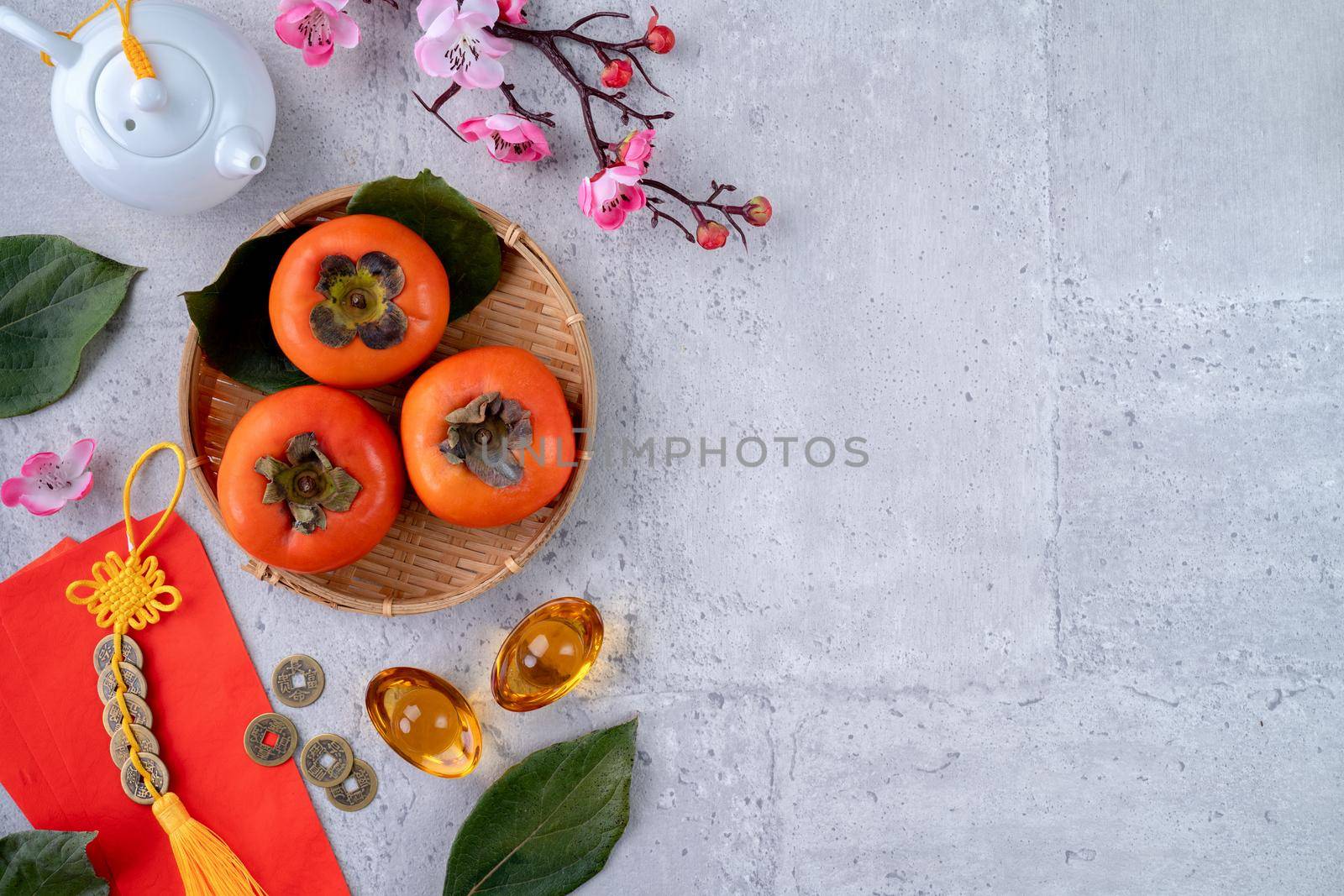 Top view of fresh sweet persimmons kaki with leaves on gray table background for Chinese lunar new year fruit design concept, the word means spring is coming.