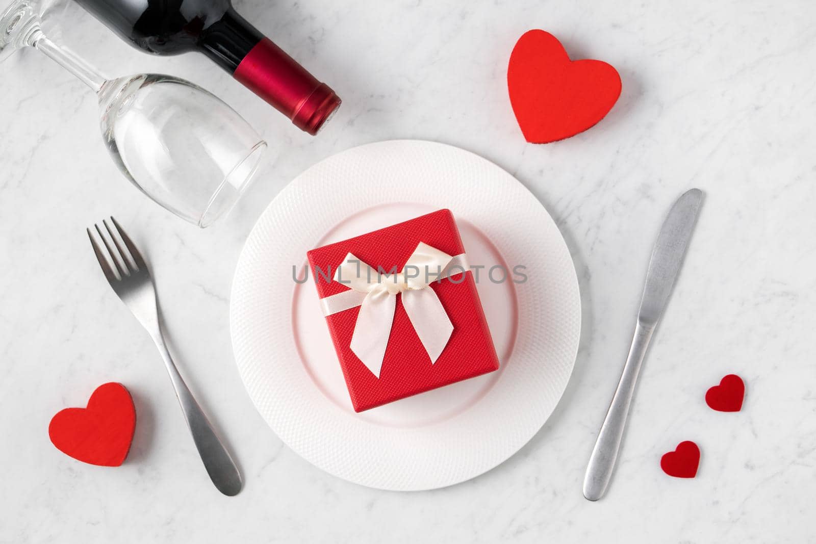 Empty white plate with tableware, ribbon, gift and roses for Valentine's Day special holiday dating meal concept.
