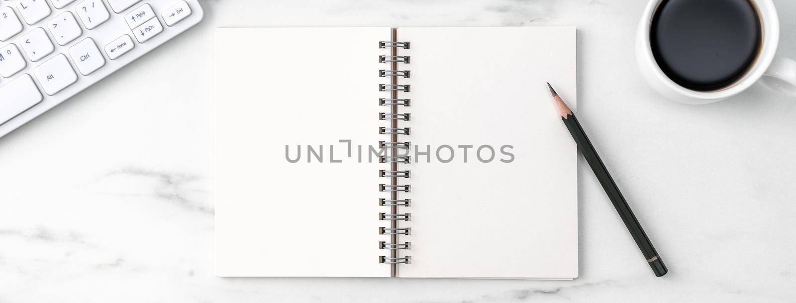 Top view of office table desk cozy work concept with keyboard, notebook, pencil, eyeglasses and coffee on bright marble white background.