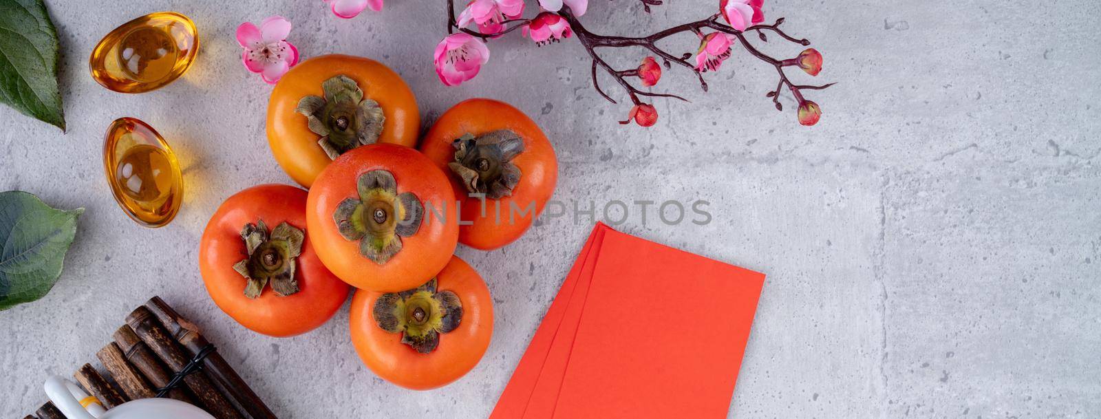 Top view of fresh sweet persimmons kaki with leaves on gray table background for Chinese lunar new year fruit design concept, the word means spring is coming.
