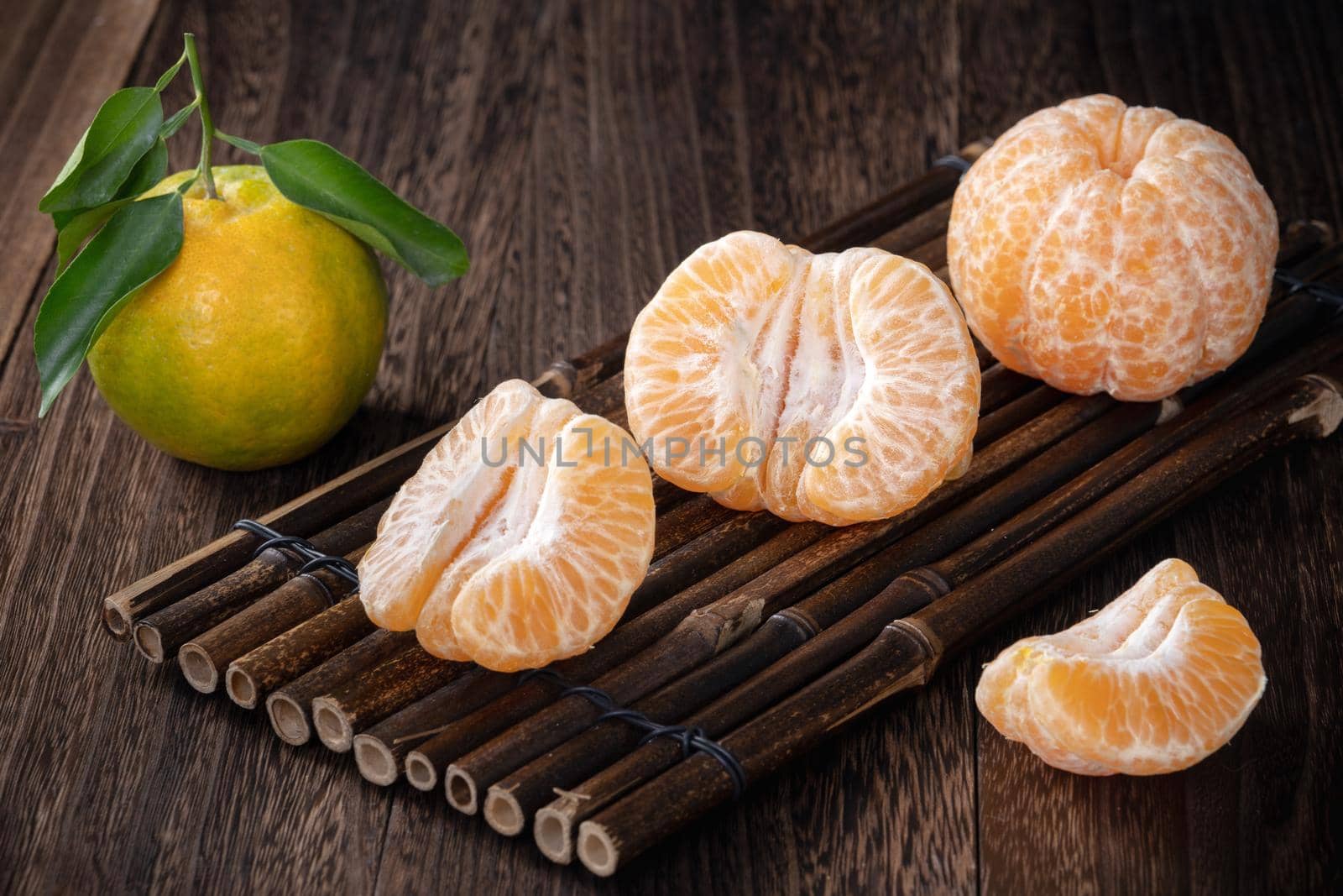 Fresh green tangerine mandarin orange with fresh leaves on dark wooden table background harvest concept.