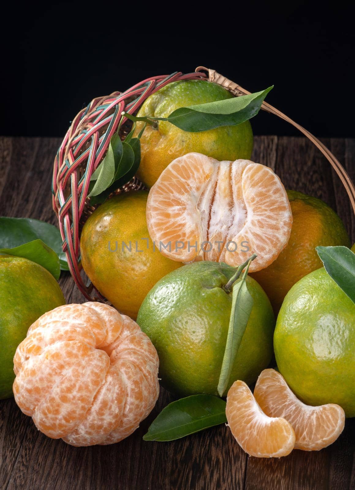 Fresh green tangerine mandarin orange with fresh leaves on dark wooden table background harvest concept.