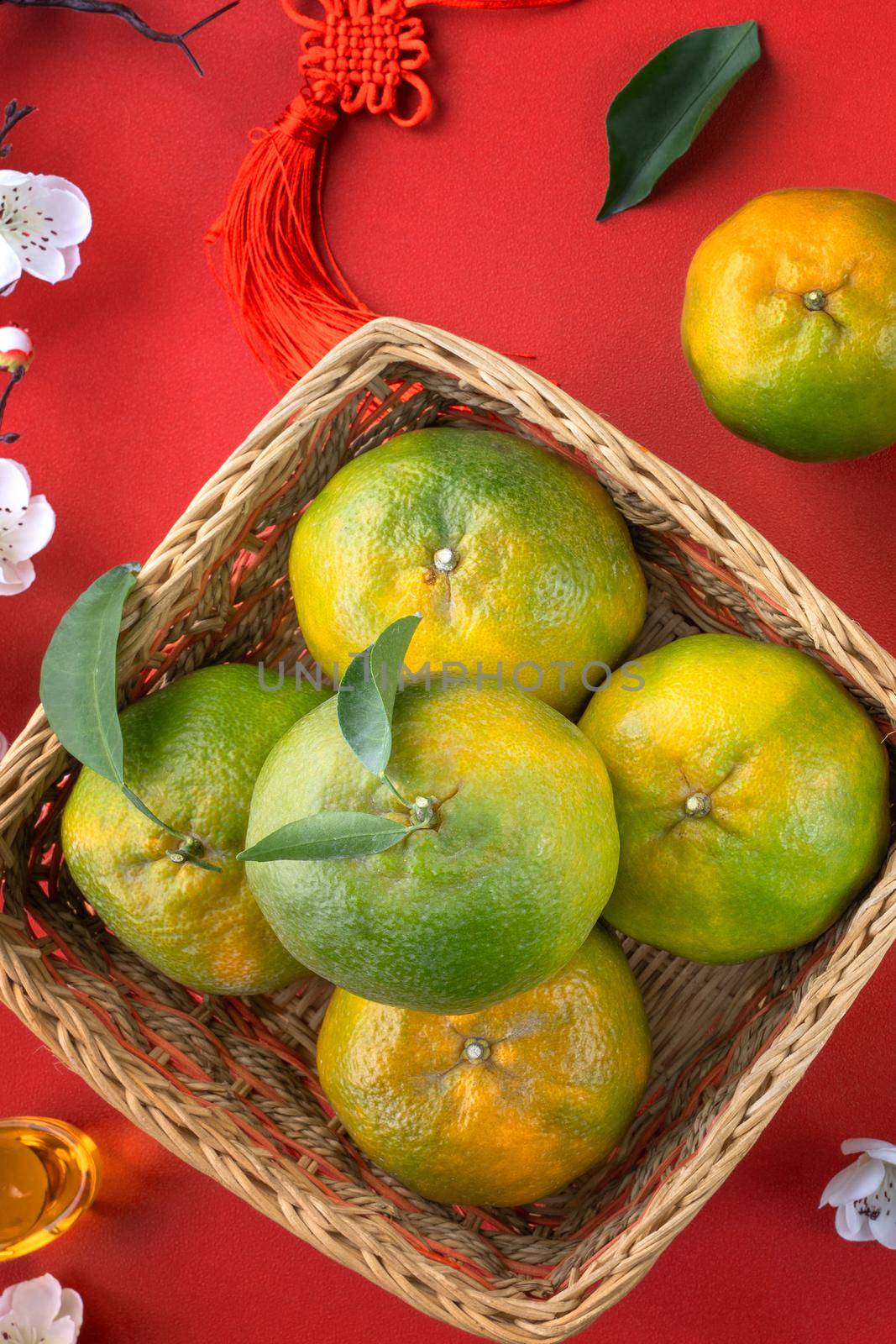 Top view of fresh ripe tangerine mandarin orange with fresh leaves on red table background for Chinese lunar new year fruit concept, the Chinese word means spring.