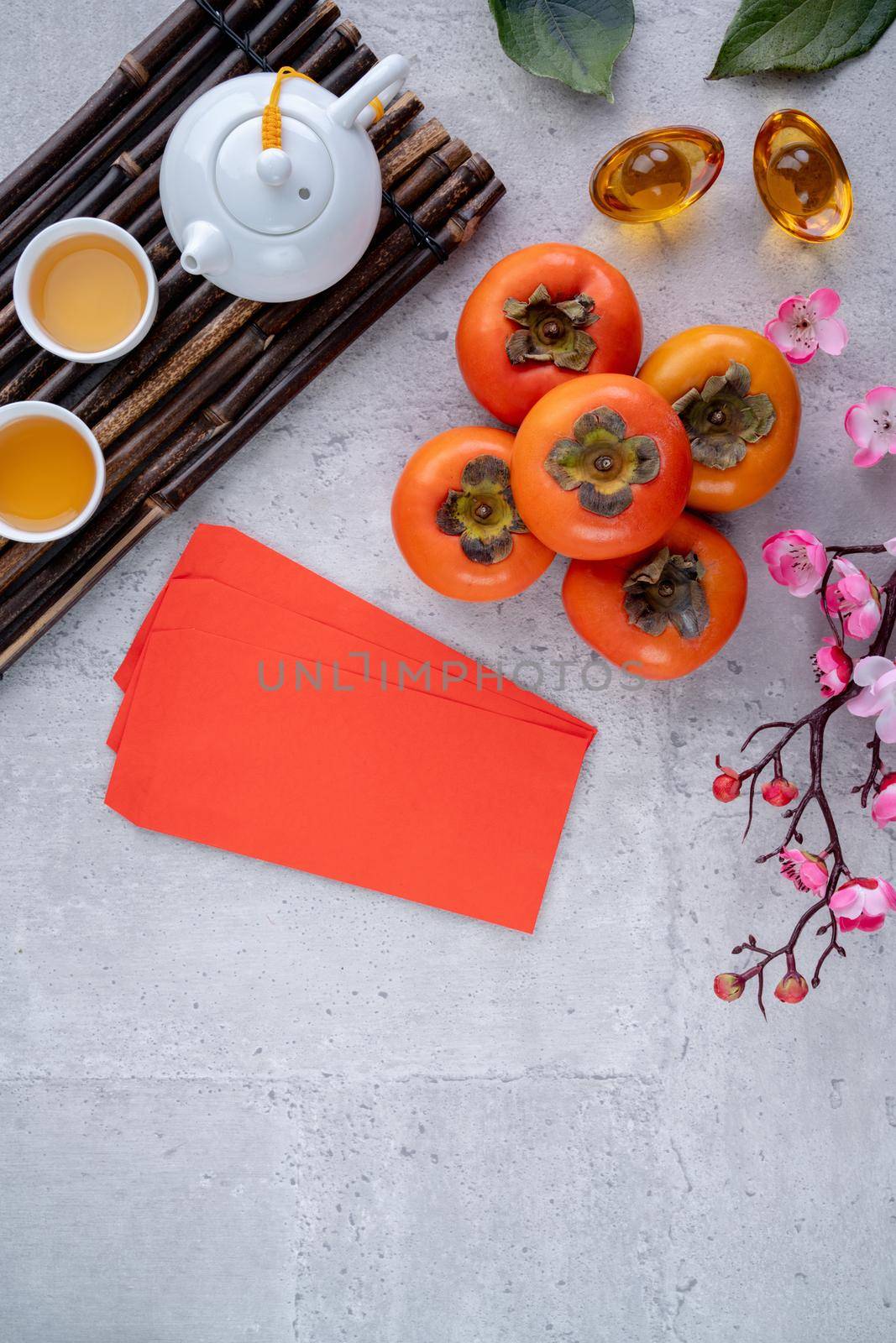 Top view of fresh sweet persimmons kaki with leaves on gray table background for Chinese lunar new year fruit design concept, the word means spring is coming.