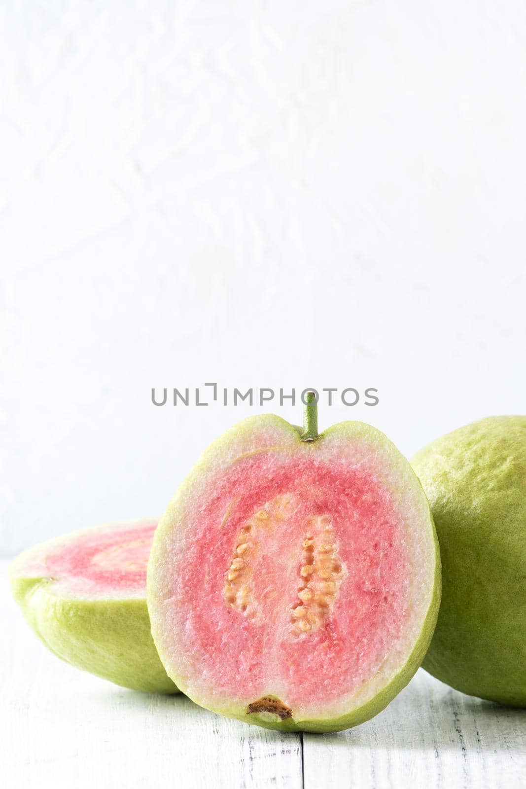 Close up of delicious beautiful Red guava with fresh green leaves isolated on white table background, studio table shot with copy space.