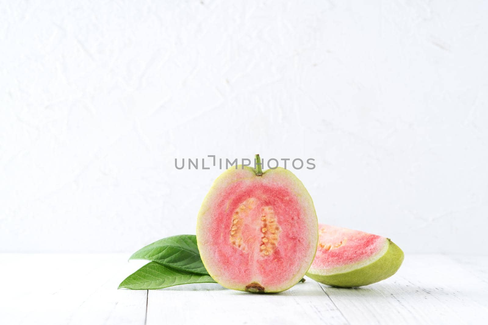 Close up of delicious beautiful Red guava with fresh green leaves isolated on white table background, studio table shot with copy space.