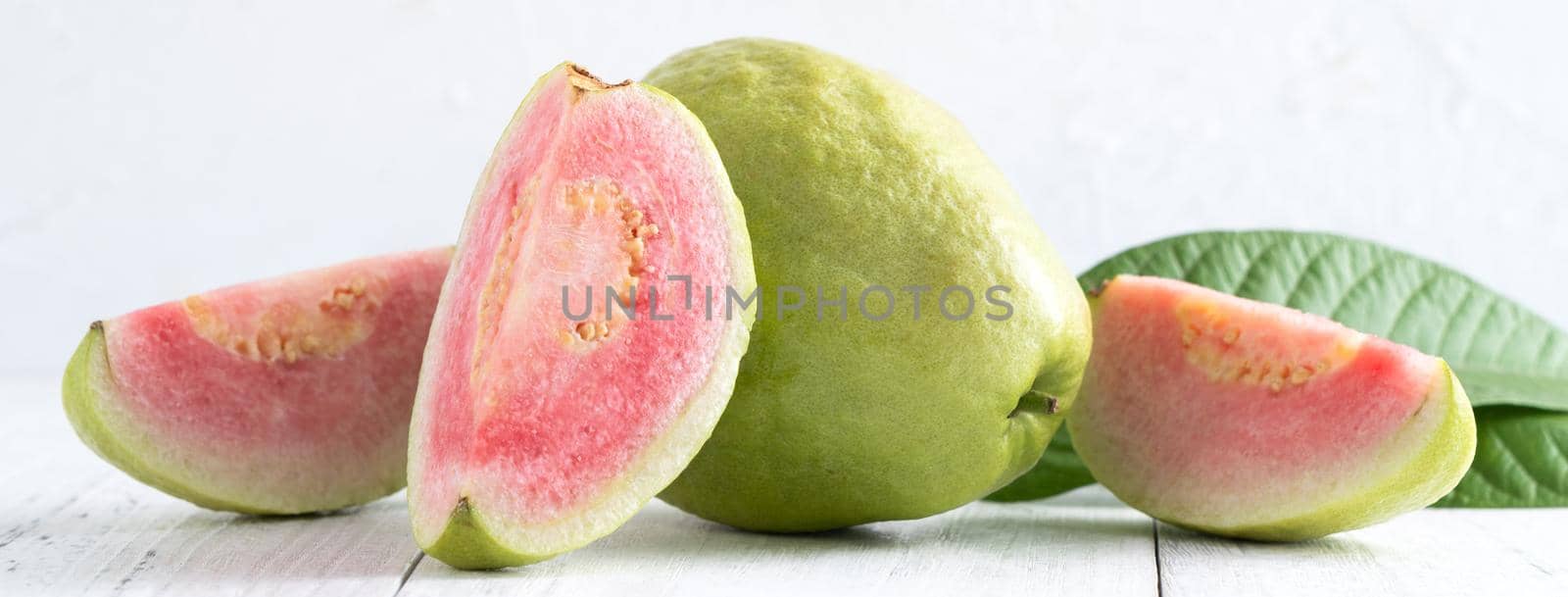 Close up of delicious beautiful Red guava with fresh green leaves isolated on white table background, studio table shot with copy space.