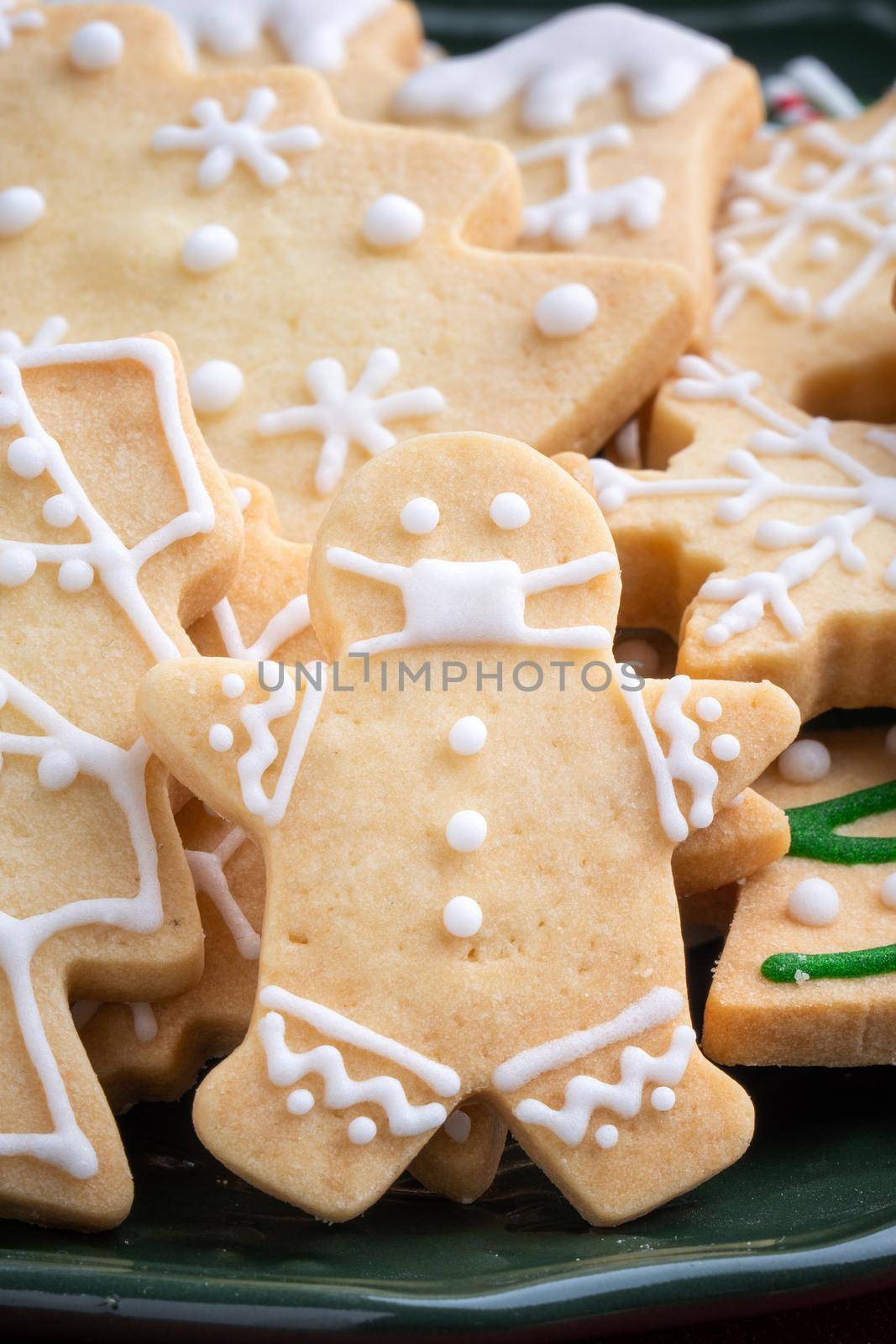 Close up of Christmas decorated sugar cookies in a plate on red table background.