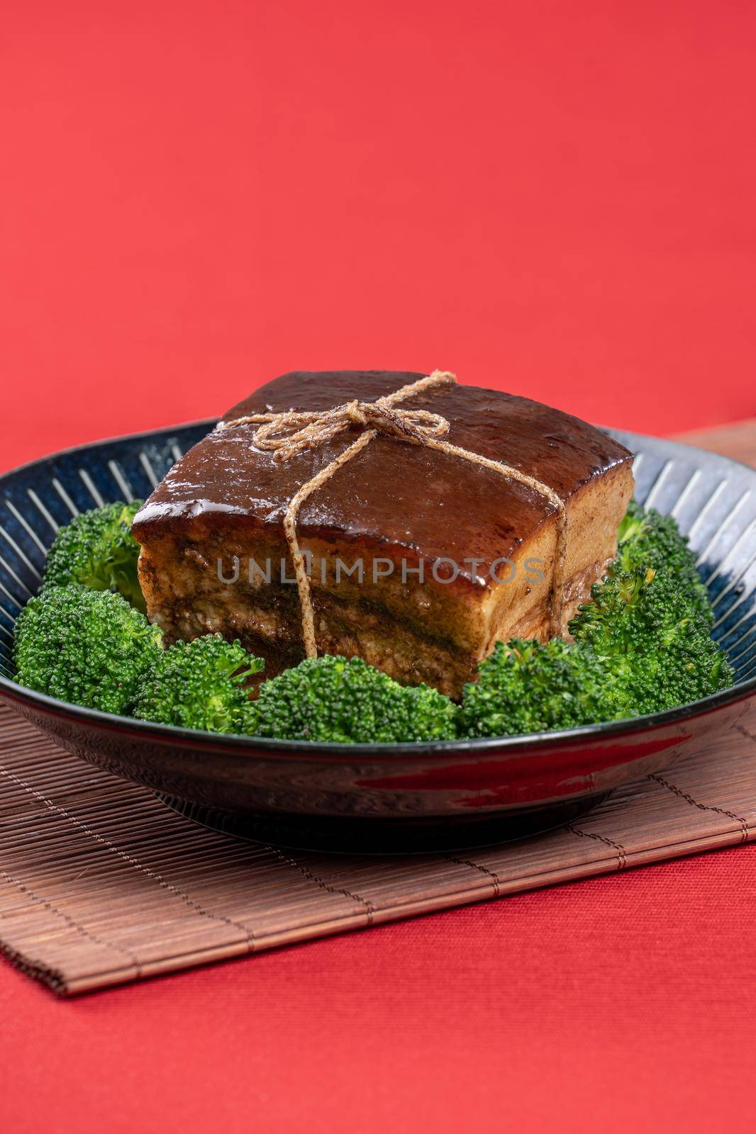 Dong Po Rou (Dongpo pork meat) in a beautiful blue plate with green broccoli vegetable, traditional festive food for Chinese new year cuisine meal, close up.