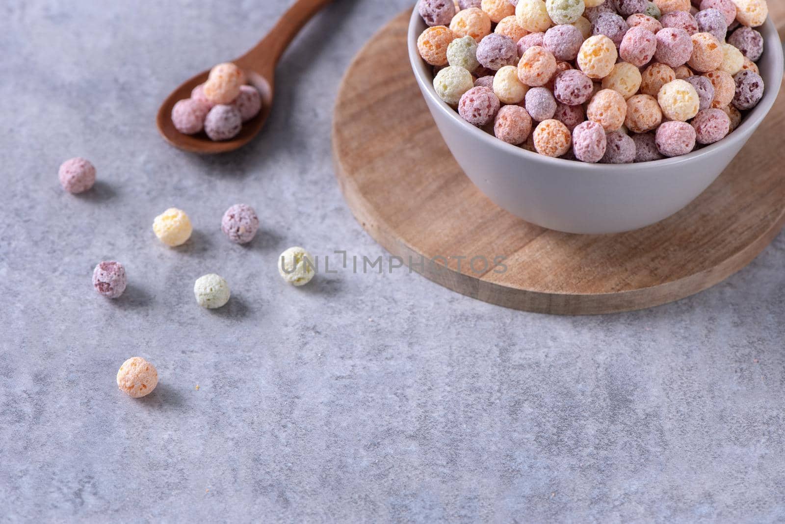 Colorful cereal corn balls mix, fruit flavor bowl sweets on gray cement background, close up, fresh, delicious and healthy breakfast, copy space design concept.