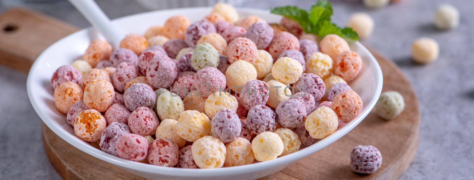 Colorful cereal corn balls mix, fruit flavor bowl sweets on gray cement background, close up, fresh, delicious and healthy breakfast, copy space design concept.