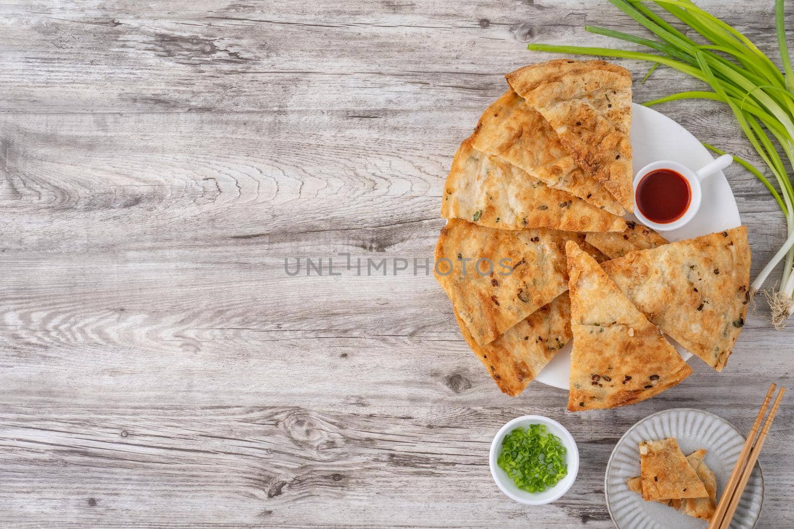 Taiwanese food - delicious flaky scallion pie pancakes on bright wooden table background, traditional snack in Taiwan, top view.