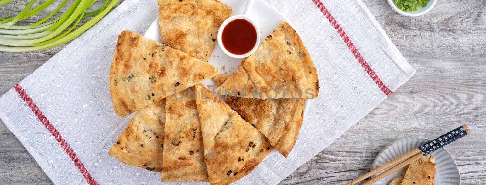 Taiwanese food - delicious flaky scallion pie pancakes on bright wooden table background, traditional snack in Taiwan, top view.