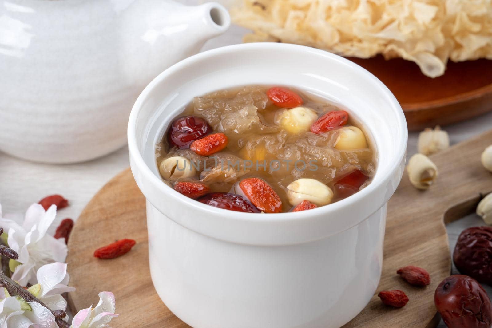 Close up of traditional Chinese sweet snow white fungus soup with lotus seed, red dates (jujube) and wolfberry (goji, gojiberry) on white background.