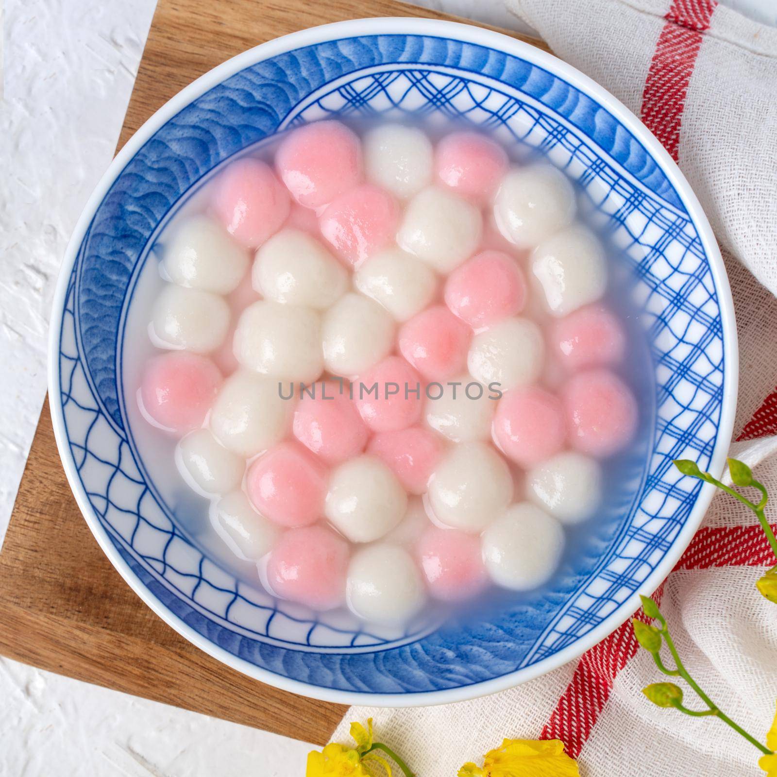 Top view of red and white tangyuan (tang yuan, glutinous rice dumpling balls) in blue bowl on white background for Winter solstice festival food.