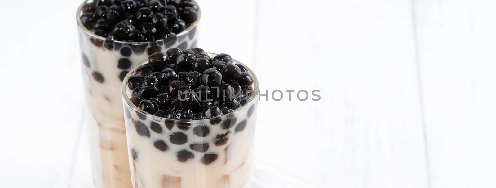 Bubble milk tea with tapioca pearl topping, famous Taiwanese drink on white wooden table background in drinking glass, close up, copy space