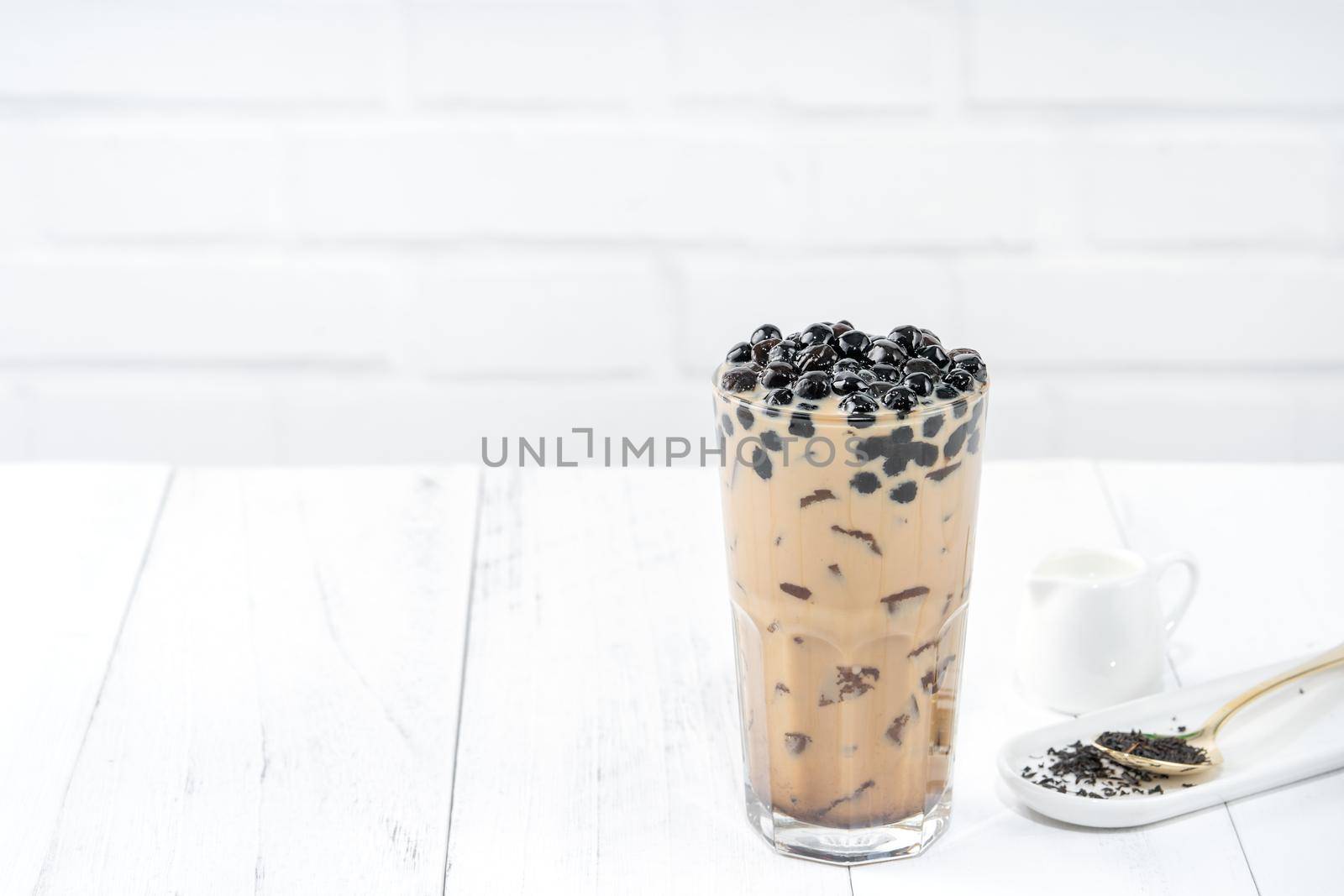 Bubble milk tea with tapioca pearl topping, famous Taiwanese drink on white wooden table background in drinking glass, close up, copy space
