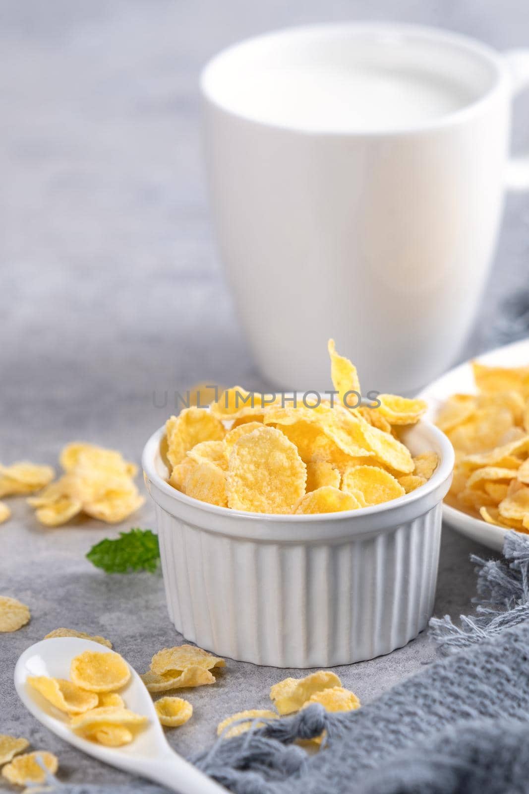 Corn flakes bowl sweeties with milk on gray cement background, close up, fresh and healthy breakfast design concept.