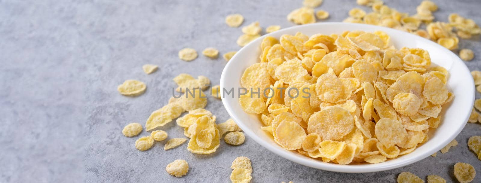 Corn flakes bowl sweeties with milk on gray cement background, close up, fresh and healthy breakfast design concept.