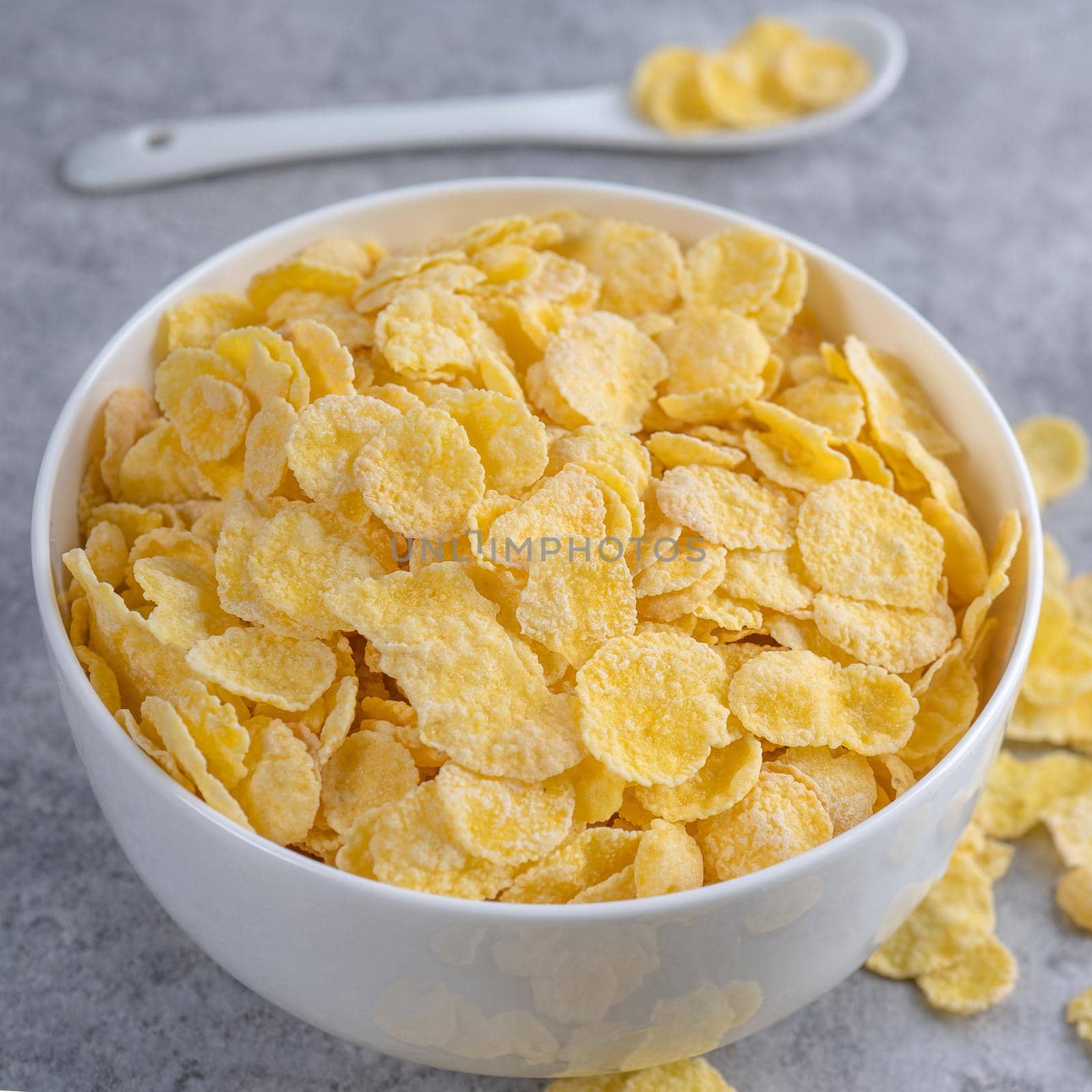 Corn flakes bowl sweeties with milk on gray cement background, close up, fresh and healthy breakfast design concept.